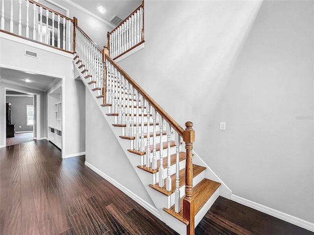 staircase with hardwood / wood-style flooring, ornamental molding, and a high ceiling