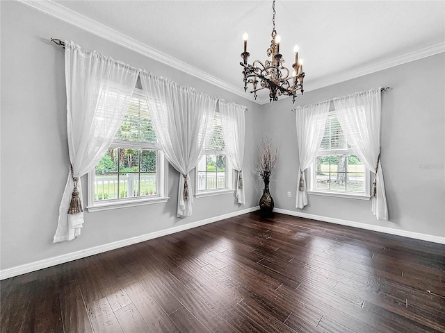 spare room featuring crown molding, dark wood-type flooring, and a chandelier