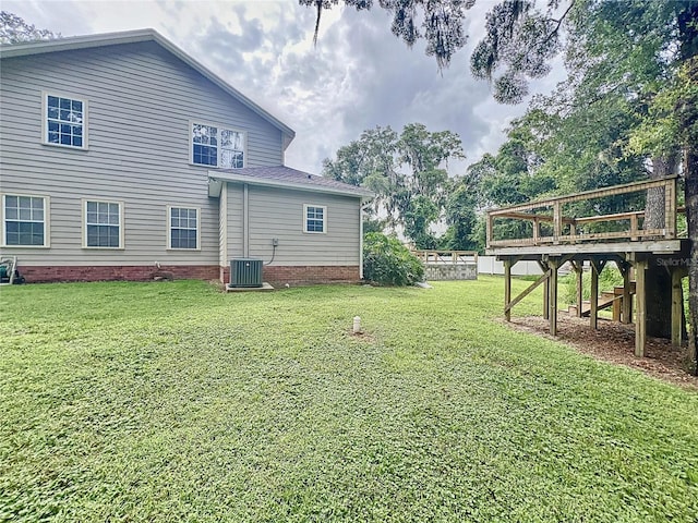 rear view of house with cooling unit, a yard, and a deck