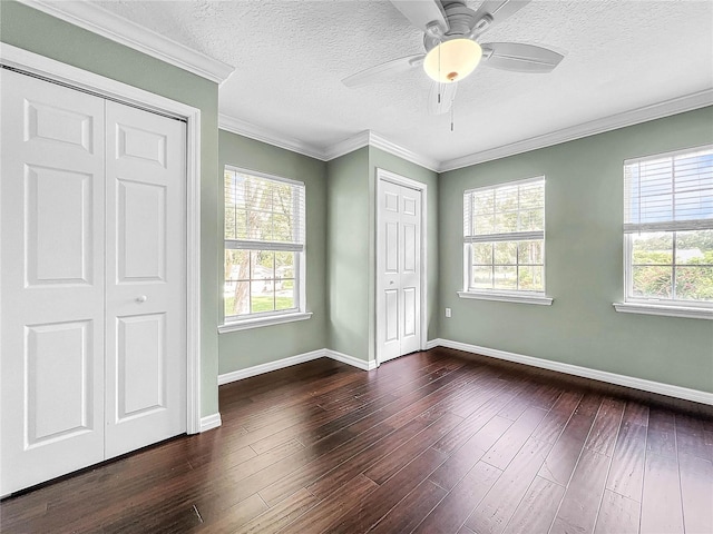 unfurnished bedroom featuring crown molding, a textured ceiling, multiple closets, dark hardwood / wood-style floors, and ceiling fan