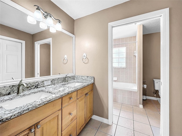 bathroom featuring tile patterned flooring, tiled tub, vanity, and toilet