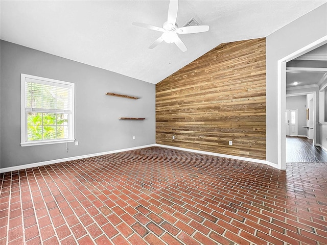 spare room with vaulted ceiling, ceiling fan, and wooden walls