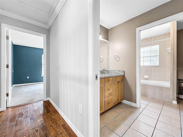 bathroom with hardwood / wood-style flooring, vanity, tiled shower / bath combo, and ornamental molding