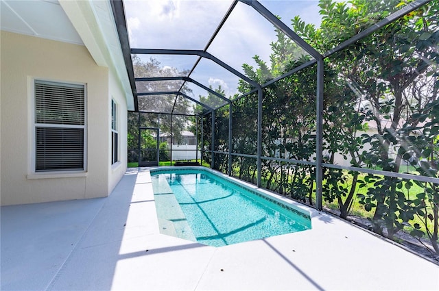 view of swimming pool featuring glass enclosure and a patio area