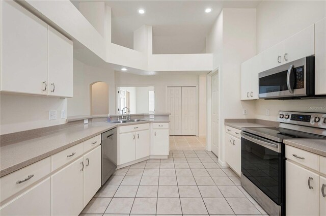 kitchen featuring appliances with stainless steel finishes, sink, white cabinets, kitchen peninsula, and light tile patterned flooring