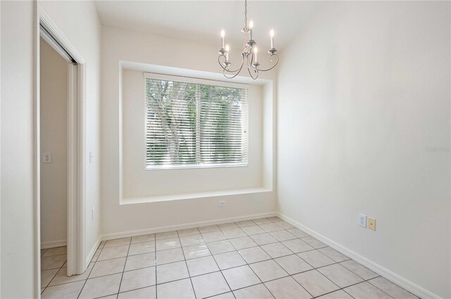 tiled empty room featuring a chandelier