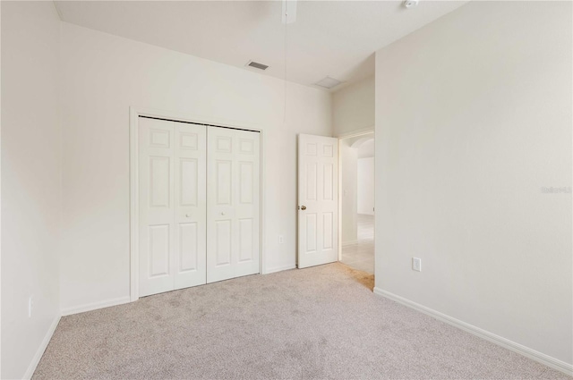 unfurnished bedroom with light colored carpet and a closet