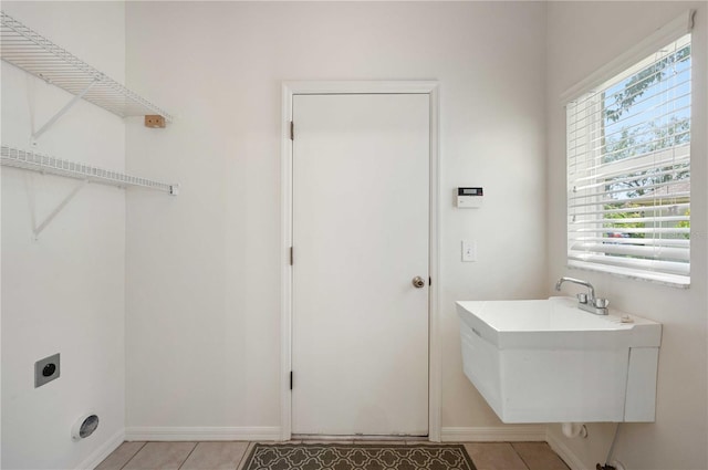 laundry room with plenty of natural light, sink, electric dryer hookup, and light tile patterned flooring