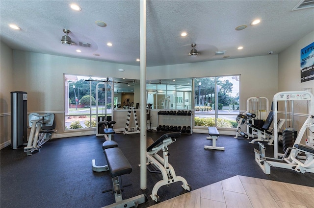 gym featuring ceiling fan and a textured ceiling