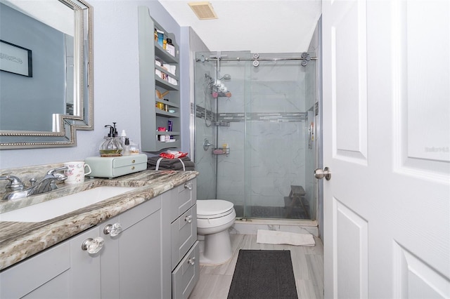 bathroom featuring vanity, a shower with door, and toilet