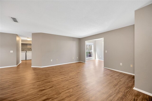 unfurnished room featuring hardwood / wood-style floors, washer and clothes dryer, and a textured ceiling