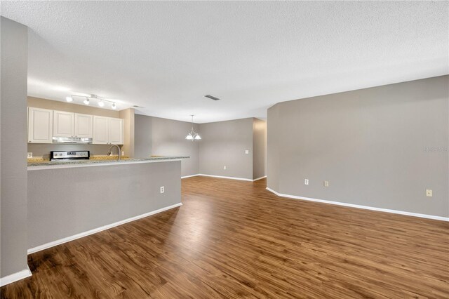 unfurnished living room with a textured ceiling, a chandelier, dark wood-type flooring, and sink