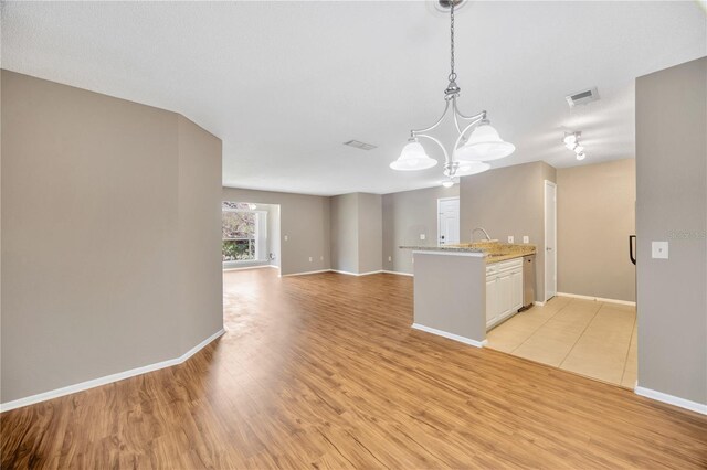 kitchen featuring light hardwood / wood-style floors, decorative light fixtures, an inviting chandelier, and white cabinets