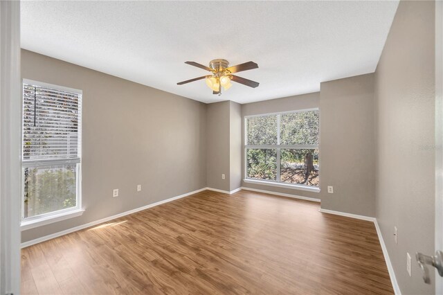 empty room with a textured ceiling, hardwood / wood-style flooring, and ceiling fan