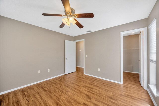 unfurnished bedroom featuring light hardwood / wood-style floors, a closet, a spacious closet, and ceiling fan