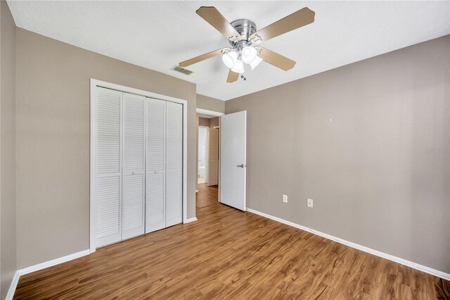 unfurnished bedroom with a closet, hardwood / wood-style flooring, and ceiling fan