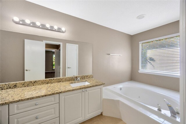 bathroom featuring vanity, a relaxing tiled tub, and tile patterned flooring