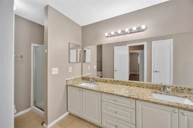 bathroom with a shower with door, a textured ceiling, toilet, vanity, and tile patterned floors