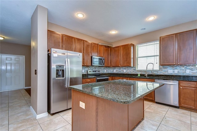 kitchen with appliances with stainless steel finishes, brown cabinetry, a kitchen island, and a sink