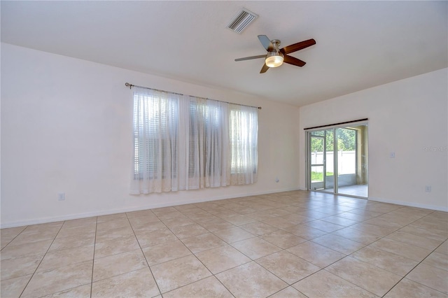 unfurnished room with light tile patterned floors, a ceiling fan, visible vents, and baseboards