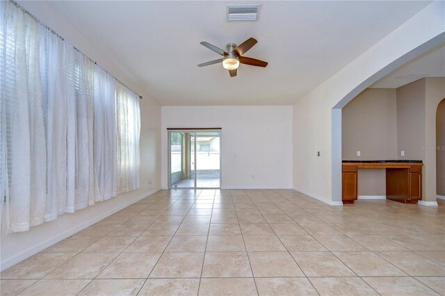 unfurnished room featuring arched walkways, visible vents, ceiling fan, and light tile patterned floors