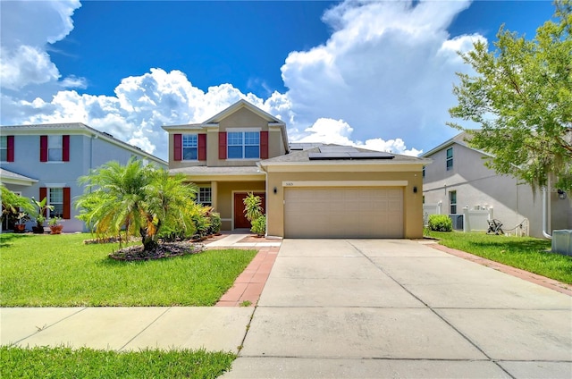 view of front of property featuring a garage, concrete driveway, roof mounted solar panels, a front lawn, and stucco siding