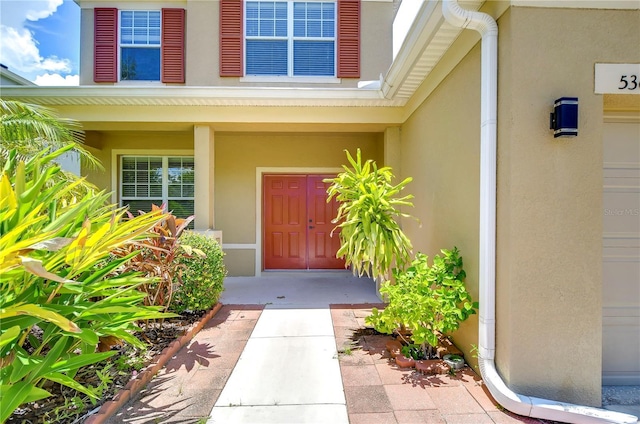 view of exterior entry with a porch and stucco siding