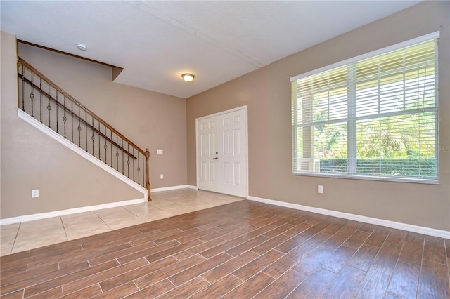 foyer entrance featuring stairway, baseboards, and wood finished floors