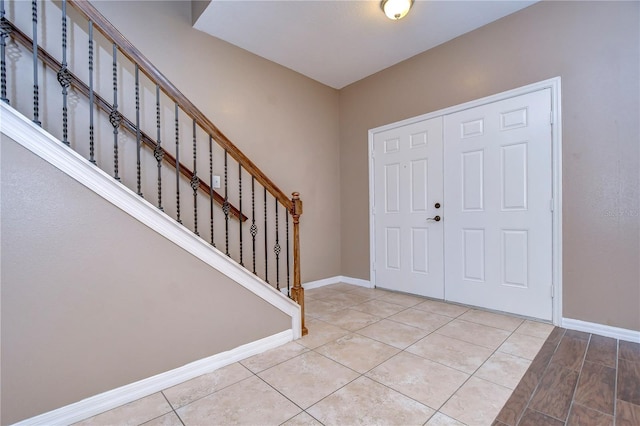 entrance foyer featuring stairs, baseboards, and light tile patterned flooring