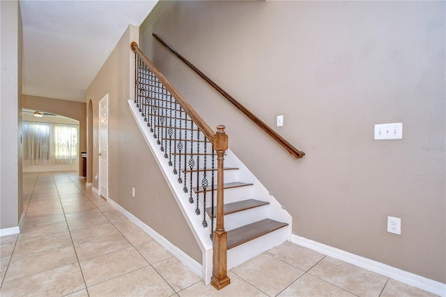 stairs featuring arched walkways, tile patterned flooring, and baseboards