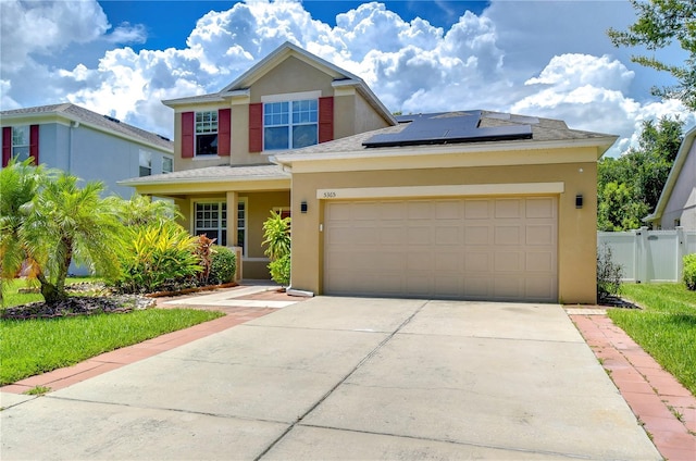 view of front of house featuring stucco siding, solar panels, concrete driveway, an attached garage, and fence