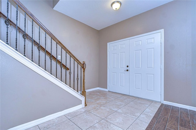 entrance foyer featuring stairs, light tile patterned floors, and baseboards