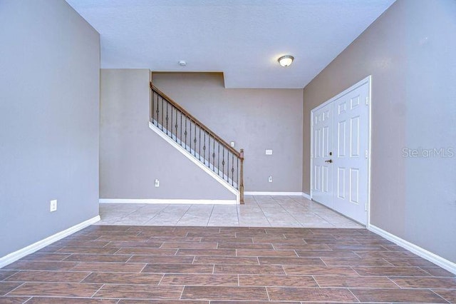 entryway featuring baseboards, stairway, and wood finish floors