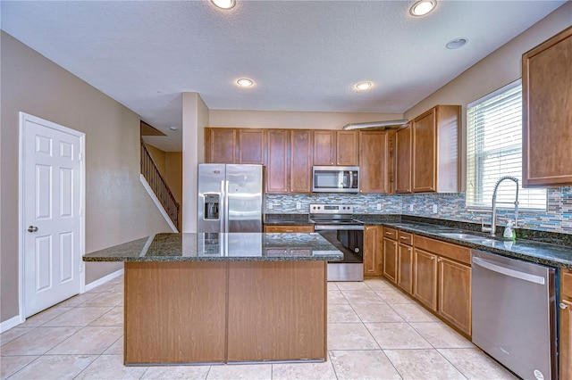 kitchen featuring appliances with stainless steel finishes, dark stone counters, and a kitchen island