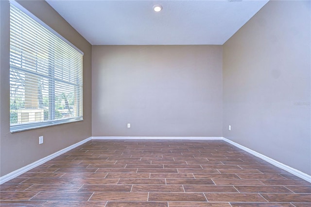 spare room featuring baseboards and dark wood-style flooring