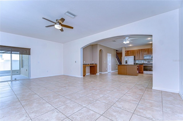 unfurnished living room featuring a ceiling fan, arched walkways, visible vents, and light tile patterned floors