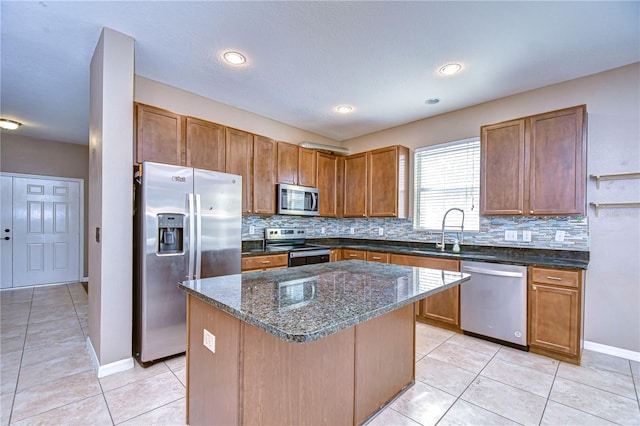 kitchen with stainless steel appliances, brown cabinetry, a kitchen island, and a sink