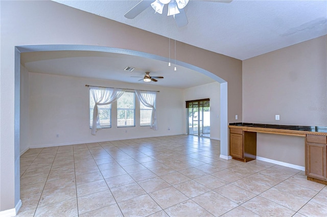 unfurnished room featuring light tile patterned floors, baseboards, visible vents, arched walkways, and a ceiling fan