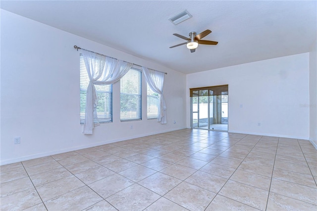 empty room featuring light tile patterned floors, ceiling fan, visible vents, and baseboards