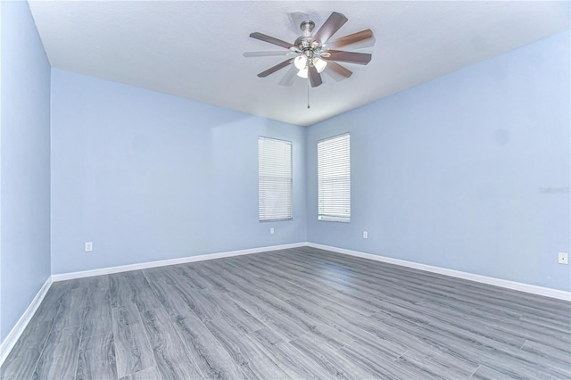 empty room with a ceiling fan, baseboards, and wood finished floors