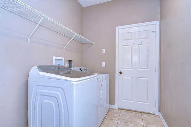 clothes washing area with light tile patterned floors, laundry area, independent washer and dryer, and baseboards