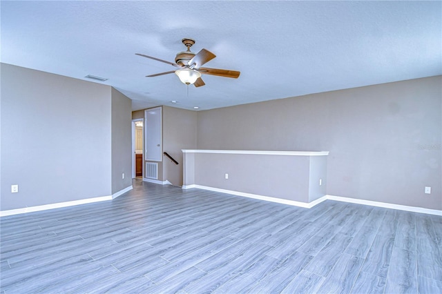 unfurnished room with baseboards, visible vents, ceiling fan, wood finished floors, and a textured ceiling