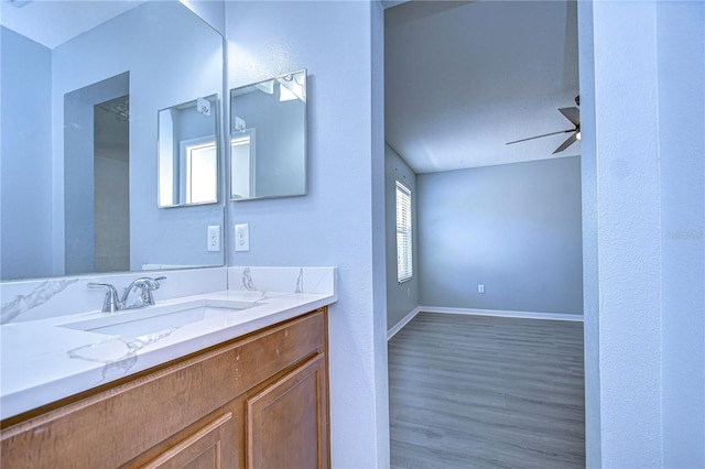 bathroom with a ceiling fan, vanity, baseboards, and wood finished floors