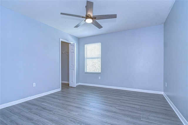 spare room featuring ceiling fan, dark wood-style floors, and baseboards