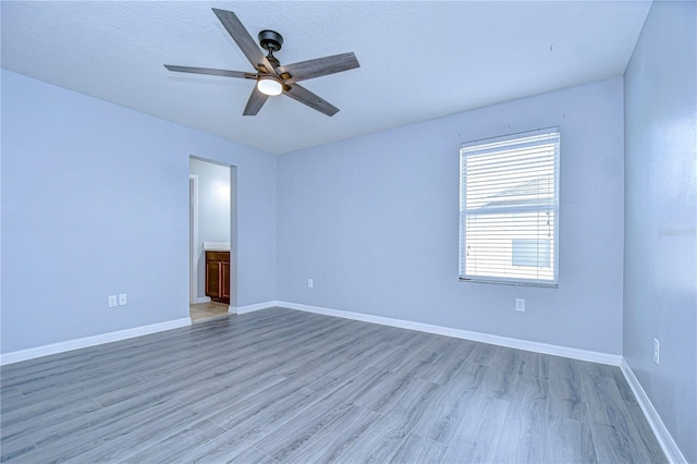 unfurnished room with ceiling fan, wood finished floors, and baseboards