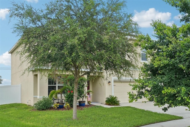 view of property hidden behind natural elements featuring a garage and a front yard