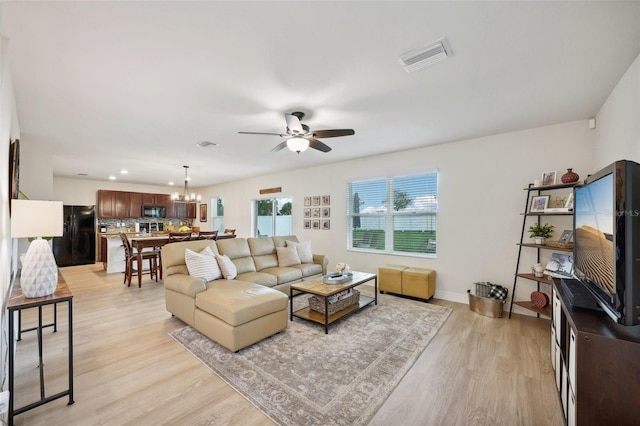 living room featuring light hardwood / wood-style floors and ceiling fan with notable chandelier