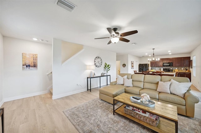 living room featuring light wood-type flooring and ceiling fan with notable chandelier