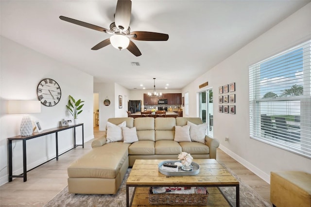 living room featuring light hardwood / wood-style floors and ceiling fan with notable chandelier