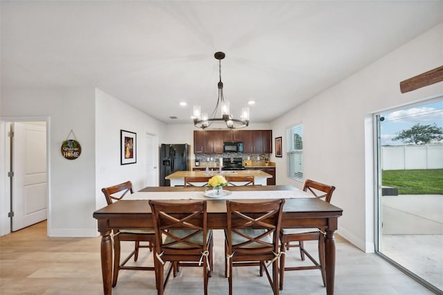 dining room with a notable chandelier, sink, and light hardwood / wood-style flooring